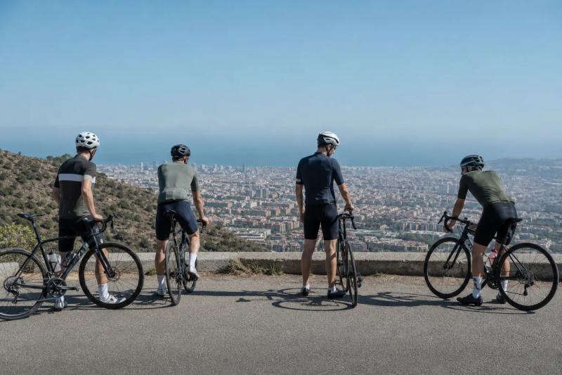 Group of road riders pausing at the top of the climb with Barcelona and the sea in the distance
