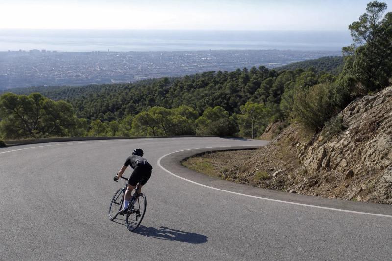 Cyclist descending a winding road on the outskirts of Barcelona in morning light