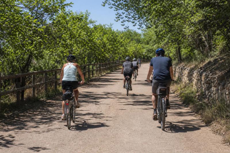 A relaxed group of riders on a tree-lined former railway path between Barcelona and the coast