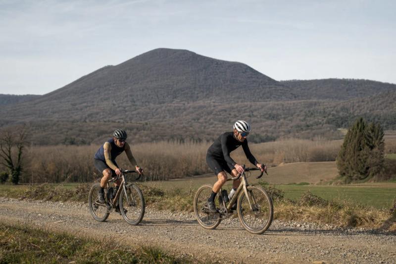 Riders on an open farm track with a volcanic cone behind them in the Garrotxa